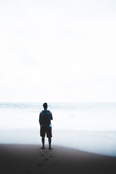 一名男子背着蓝色和黑色的背包站在水面前